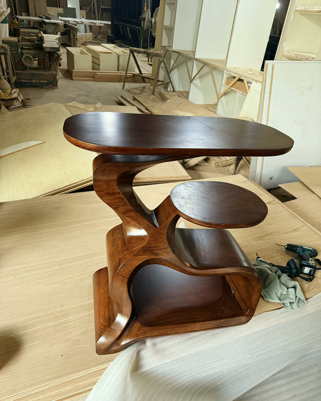 Sculpted wooden side table photographed on the Timber Vintique workshop floor